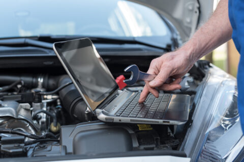 Mechanic using laptop for checking car engine